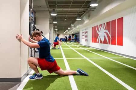 An athlete stretches on an indoor track