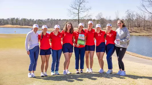 The women's golf team poses on a green after winning the Chris Banister Classic