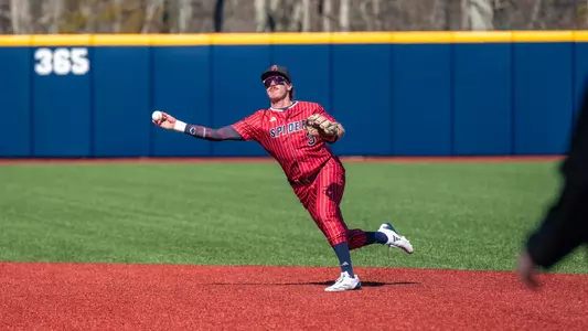 Michael Elko throws the ball from his spot near second base towards first wearing Spiders red uniform with white pinstripes