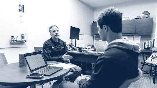 Bruce Matthews discusses classwork with a student