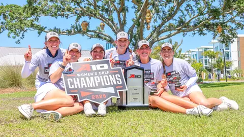 Members of the women's golf team pose with the 2025 A-10 Women's Golf Championship trophy