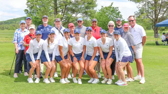 Members of the 2024-25 women's golf team and their supporters pose on the course in Charlottesville