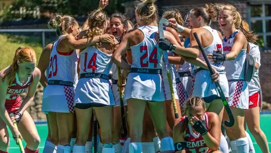 The Spiders field hockey team celebrates in a huddle after defeating Temple