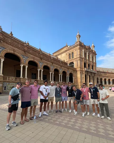 Men's lacrosse players pose in front of a square in Europe