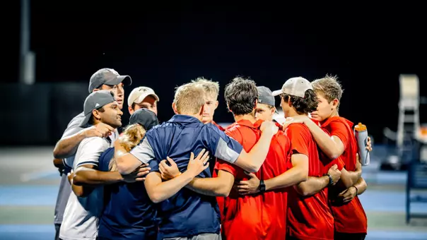 A photo of the men's tennis team in a huddle