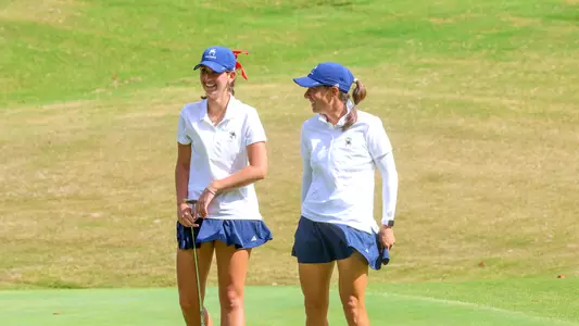 Calle Barlow and Katie Magner laugh on the putting green