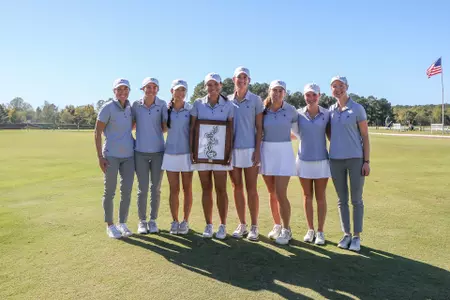The women's golf team poses with the trophy after winning a share of the Spider Invitational