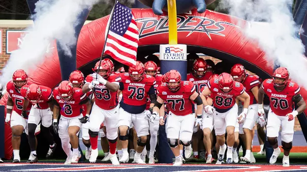 Football team running out of the inflatable Spider tunnel against Fordham on Sept. 26, 2026