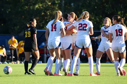 The women's soccer team celebrates together following a goal