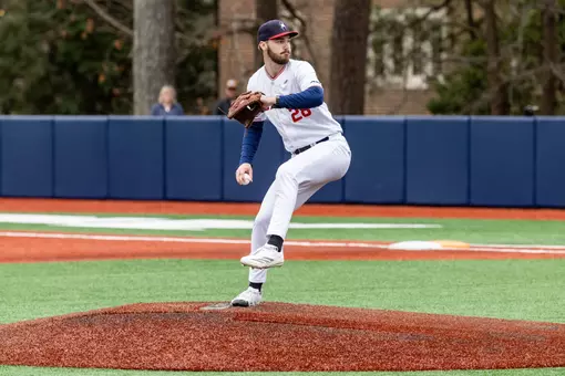 Justin Gay wearing Spider Baseball home all white uniform strides towards home plate and pushes off the mound
