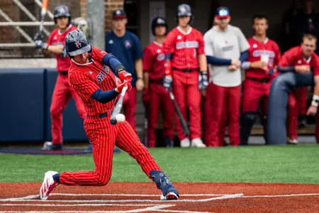 Grant Kennedy wearing the Spiders all red with white pin stripes uniform swings his bat and makes contact with the ball