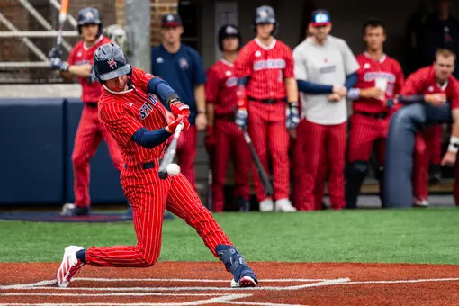 Grant Kennedy wearing the Spiders all red with white pin stripes uniform swings his bat and makes contact with the ball