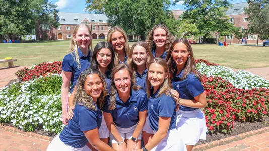 The 2025-26 women's golf team gathers in front of a fountain on campus