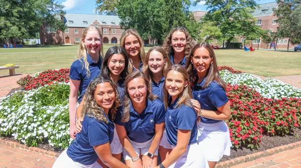 The 2025-26 women's golf team gathers in front of a fountain on campus