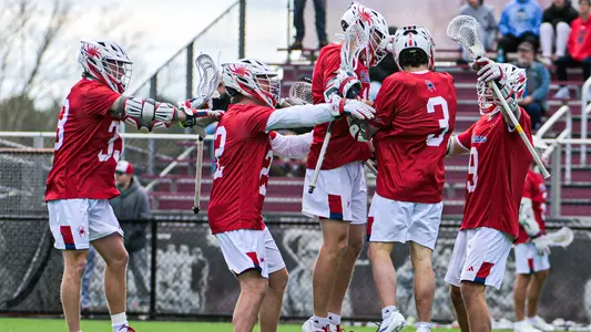 Men's lacrosse players celebrate a goal against UMass on March 21