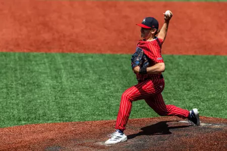 Jackson Hinchliffe holds the ball behind his head, ready to throw the ball towards home plate.
