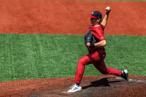 Jackson Hinchliffe holds the ball behind his head, ready to throw the ball towards home plate.