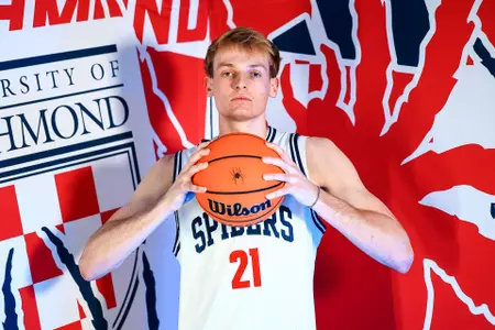 Andrew Ball holds a basketball in front of his chin and stairs at the camera