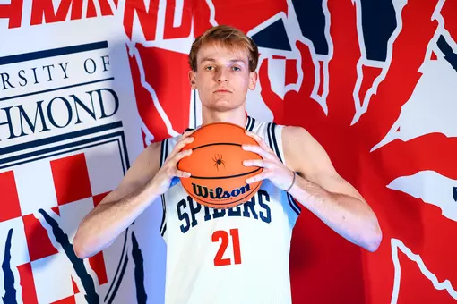 Andrew Ball holds a basketball in front of his chin and stairs at the camera