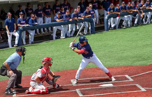 Dylan Winebrenner stands at the plate while the Spiders dugout watches his at bat
