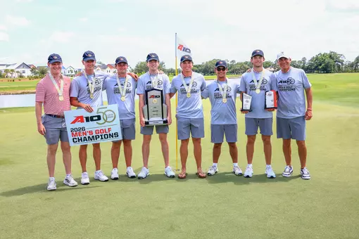 Members of the Richmond men's golf team pose with a trophy on the green