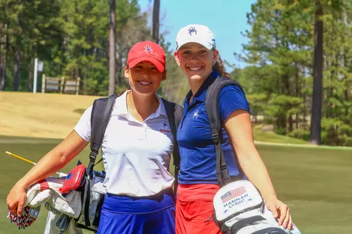 Olivia Wilkie and Hannah Lydic smile at the camera on the green
