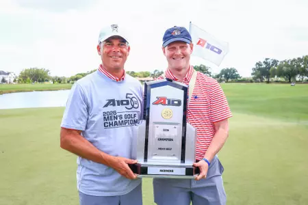 Adam Decker and Cole Ekert pose with the A-10 trophy on the green at Evermore Resort