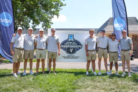 The men's golf team poses in front of an NCAA Regional sign at Bermuda Run Country Club