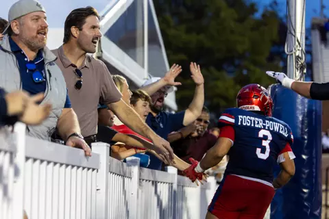 A fan slaps hands with a Spider who just scored a touchdown