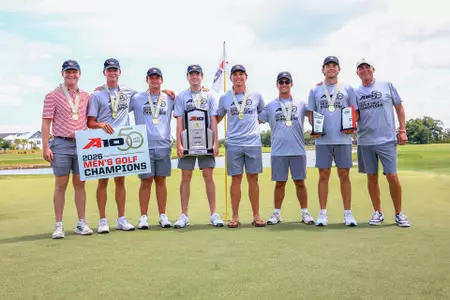 The men's golf team poses on the green after winning the A-10 Championship.