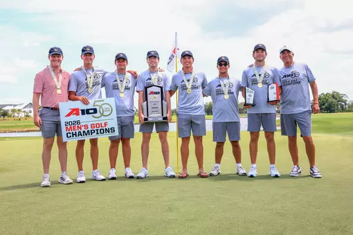 The men's golf team poses on the green after winning the A-10 Championship.