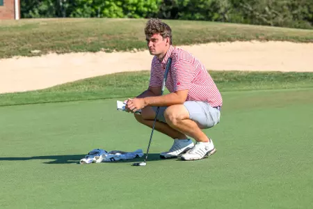 Jack LaPiana squats on the green