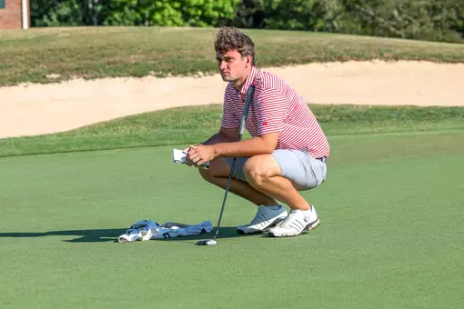 Jack LaPiana squats on the green