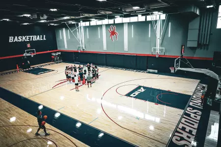 The men's basketball team huddles during a practice in Queally Athletics Center