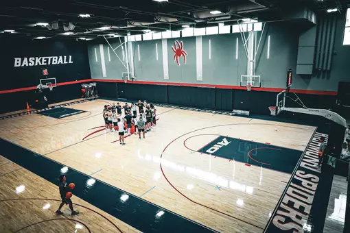 The men's basketball team huddles during a practice in Queally Athletics Center