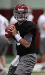 AJ McCarron drops back during Friday's drills inside the Hank Crisp Indoor Facility.