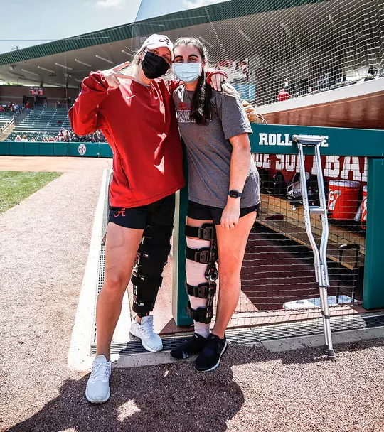 Bailey Dowling and Claire Jenkins posing together, both with knee braces on their leg