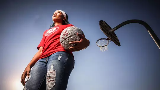 Alabama Guard Brittany Davis holding a jeweled basketball in front of a basketball goal