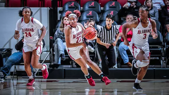 Brittany Davis dribbling down the court flanked by De'Sha Benjamin and Jordan Lewis