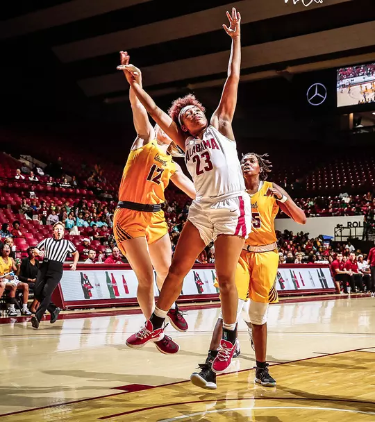Alabama Guard Brittany Davis in the air in front of two opposing players