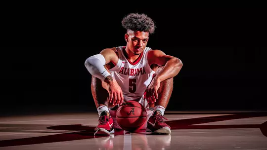 Jaden Shackelford sitting on the court with a basketball
