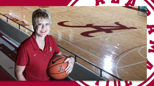 Kristy Curry holding a basketball with the court in the background