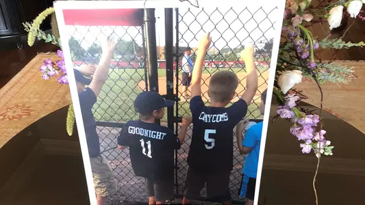 Photograph of Mason Goodnight and Canon Claycomb as children outside the fence of a baseball game