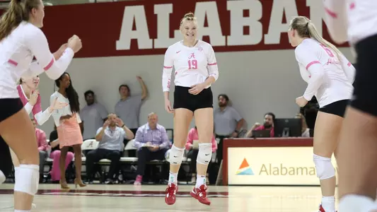 Alabama volleyball player Kendyl Reaugh smiles with teammates on the court after getting a point.