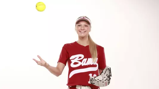 Alabama softball player Abby Duscherer throws softball in air.