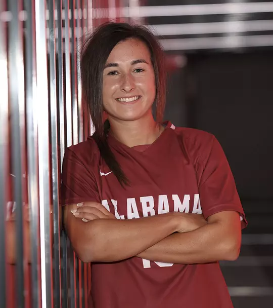 Kat Rogers leaning against a wall in a red jersey