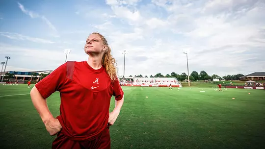 Riley Mattingly looking off into the distance with the field behind her