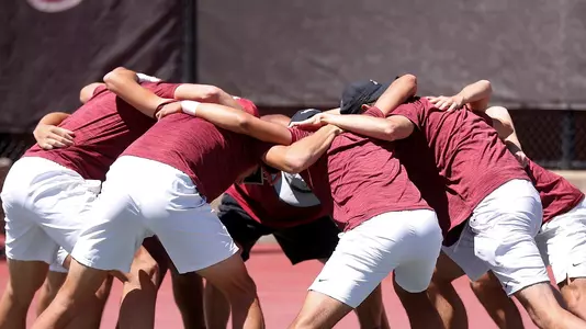 The men's tennis team gathers together prematch for a team cheer