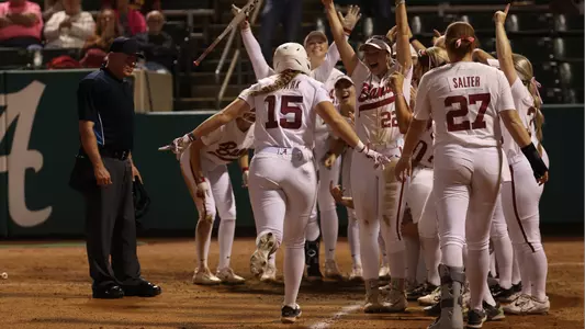 Alabama softball players await Kendal Clark at home plate after a home run vs. Jones College (Oct. 20, 2023)