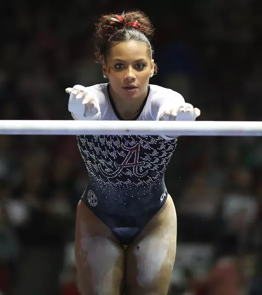 Makarri Doggette with arms outstretched ready to grab the uneven bars